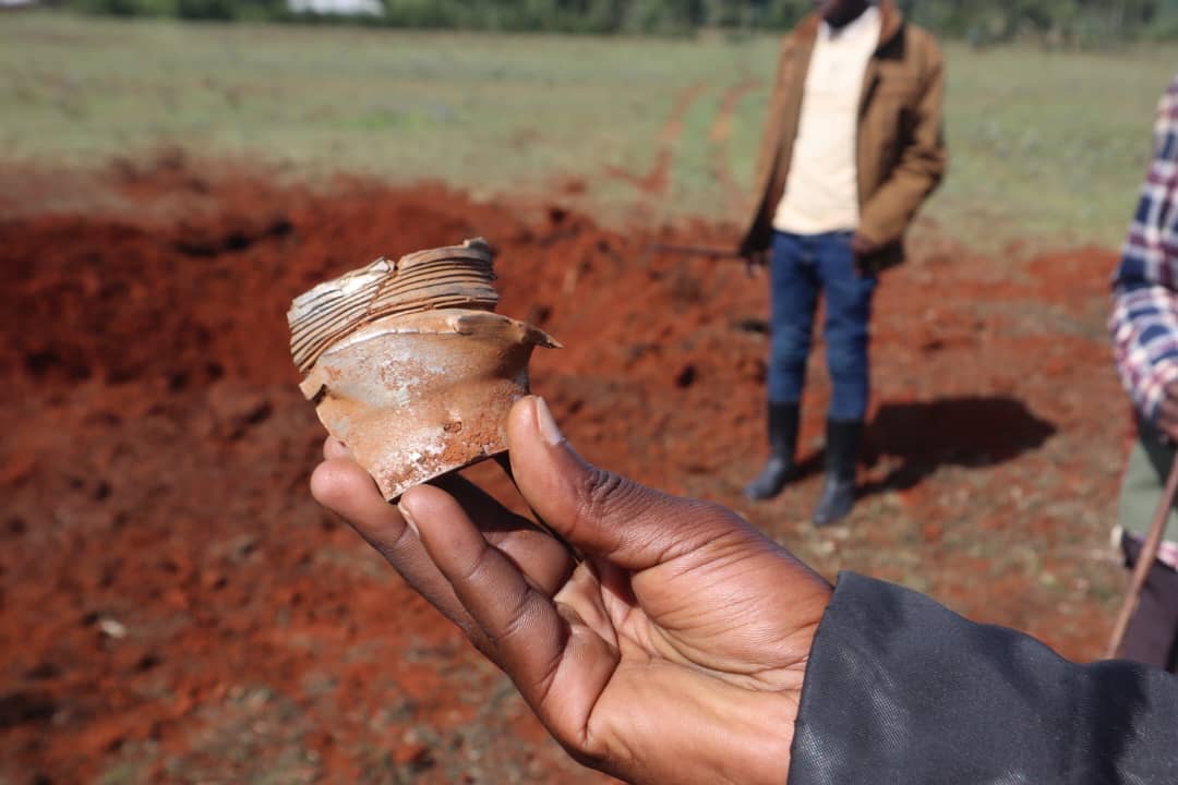 A hand holding a broken clay object outdoors
